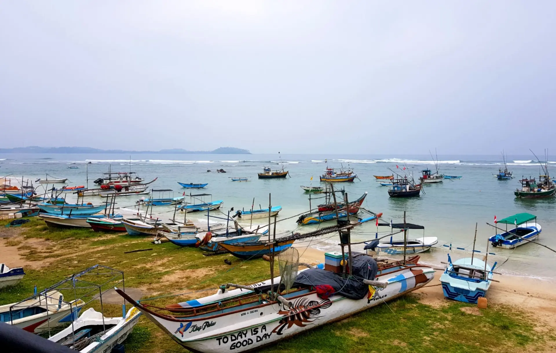 Färgglada fiskebåtar i viken vid Weligama